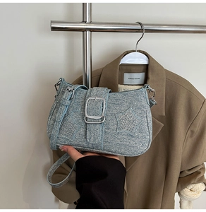 Detailed shot of Y2K blue denim shoulder bag with silver star studs and large buckle