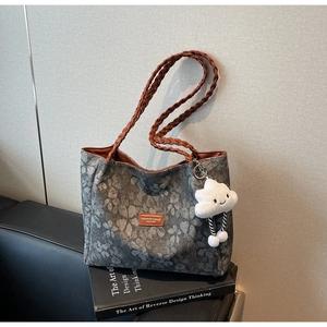 Detailed view of grey tote bag with brown woven straps and cloud plush charm
