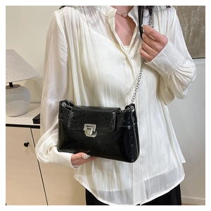 Détail d'un sac bandoulière noir texture crocodile avec chaîne et fermoir en métal argent