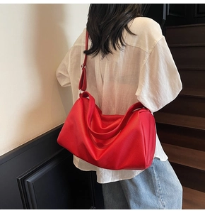 Detail of red pebbled leather shoulder bag showing large capacity and soft texture on model