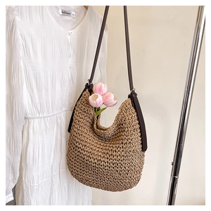 Gros plan détaillé d'un sac seau en raphia marron avec bandoulière et tulipes roses