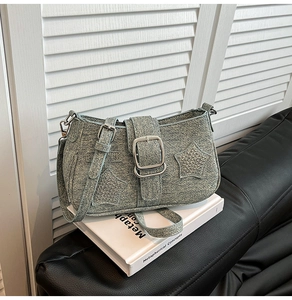 Detail of light blue denim shoulder bag with silver square buckle and star rivet patches