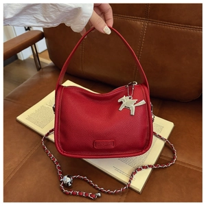 Detail of red litchi grain leather bag with silver horse charm and chain strap