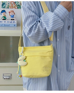 Dettaglio della borsa tote in nylon giallo con ricamo di lettere e ciondolo a luna