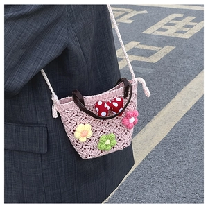Detail of pink crochet bucket bag with bow and flower charms worn by model