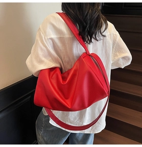 Rear view of a model wearing a large red pebbled leather tote bag on a wooden staircase