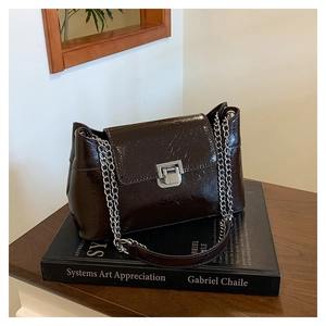 Détail du sac en cuir verni marron foncé avec texture vintage et fermoir carré argenté