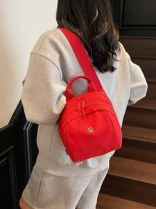 Red nylon mini shell bag with wide shoulder strap and metal logo worn on back