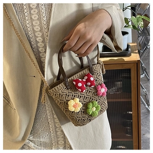 Detail of handmade crochet mini bucket bag with floral accents and leather handle