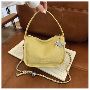 Close-up of yellow lychee leather handbag with chain strap and Pegasus metal charm