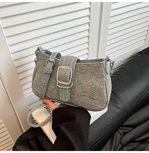 Detail of light blue denim crossbody bag with star studs and wide buckle strap design