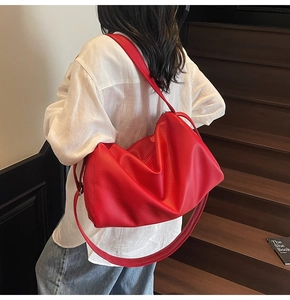 Detailed close-up of a large red lychee leather shoulder bag on a model in casual setting