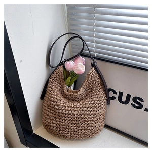 Détail du sac seau en paille tressée avec bandoulière en cuir marron et tulipes roses
