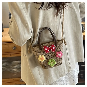 Detail of hand-woven straw bucket bag with crochet floral accents and polka dot bow