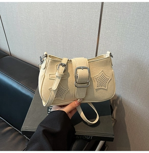 Detail of cream white leather shoulder bag with star rivets and silver square buckle