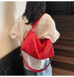 Detailed view of red hobo bag with litchi grain texture on wide shoulder strap