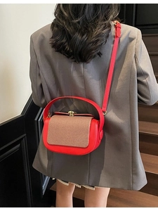 Fashionable red pillow bag with brown woven flap and golden buckle on grey suit model