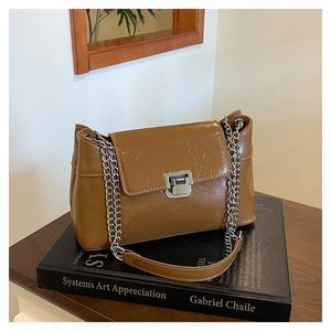 Détail d'un sac bandoulière en cuir huilé marron avec texture vintage et fermoir argenté