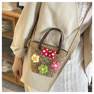 Detail of woven straw bucket bag featuring colorful crochet flowers and red polka dot bow