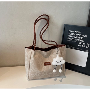 Detail of beige tote bag featuring floral texture, woven straps and cloud charm