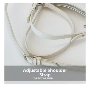 Close-up of white leather handbag featuring adjustable shoulder strap with silver buckle
