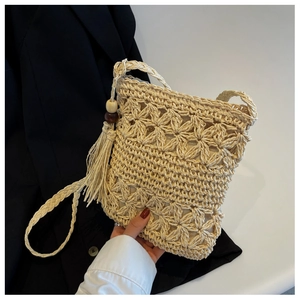 Détail du sac en paille ajouré avec gland en perles de bois et bandoulière tressée