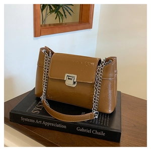 Gros plan du sac bandoulière marron texture crocodile avec chaîne argentée