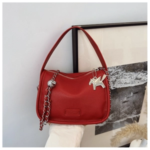 Detailed view of red pebble leather hobo bag with silver chain and unique charms