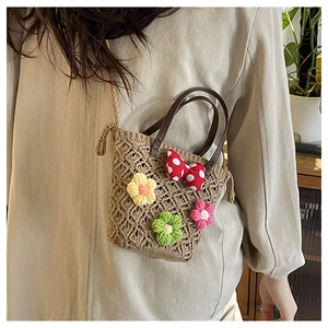 Detail of floral woven beach bag with colorful crochet flowers and leather handles