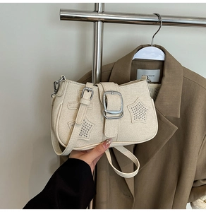 Detail of off-white Y2K shoulder bag with star rivets and silver buckle on a tan blazer
