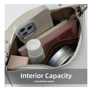 Internal capacity detail of white faux leather bag with compartments for phone and cosmetics
