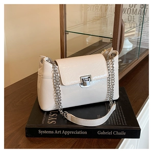 Détail du sac à bandoulière en cuir verni crème avec texture plissée et chaîne argentée