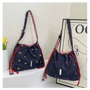 Detail of denim bucket bags featuring floral cherry prints and red gingham straps