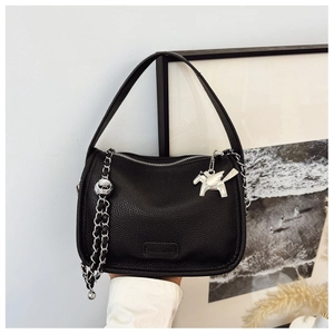 Detail of black litchi leather handbag with silver chain and iconic pegasus charm