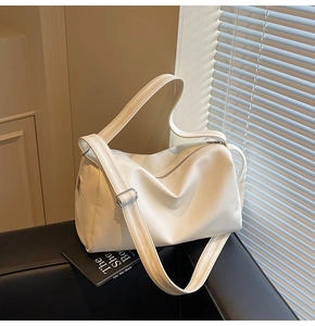 Detail of white lychee pattern leather texture on a minimalist hobo bag with silver buckle