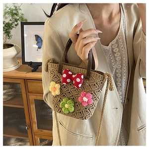 Detail view of handmade woven straw bucket bag with floral crochet and red bow