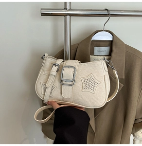 Detail view of cream armpit bag with star patches, silver rivets and metal buckle