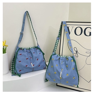 Detail of floral and cherry canvas bucket bags with green checkered lining and drawstring