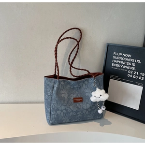 Detail of floral canvas tote bag with woven handles and cute cloud plush charm