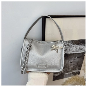Detail of silver pebble grain leather bag with metal chain and Pegasus charm