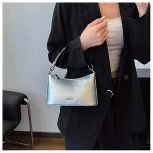 Detailed view of silver metallic crescent bag with brand logo shown on model's shoulder