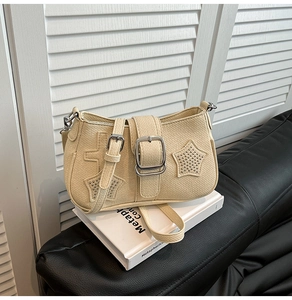 Detail of beige faux leather bag with metal stars, cross charms and silver hardware