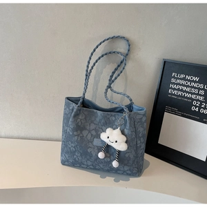 Detail of light blue floral tote bag with textured fabric and cloud charm accessory