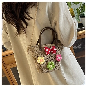 Detail of woven straw bucket bag with floral crochet accents and a red polka dot bow