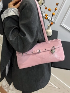 Pink Y2K shoulder bag with silver heart pendant and buckle detail on a female model