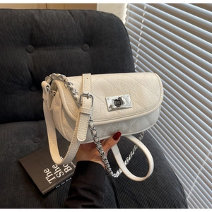 Detail view of white quilted mini chain bag with silver clasp and leather strap texture