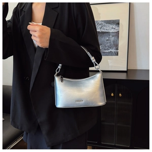 Detail of silver metallic CAHEKA shoulder bag with embossed logo and glossy mirror finish