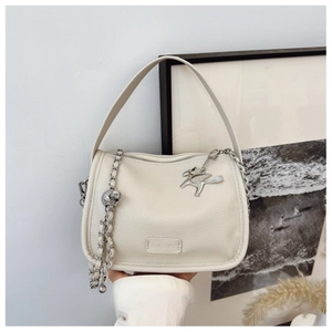 Detail of cream lychee leather handbag with silver chain and horse charm accessory