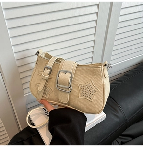 Detail of beige leather shoulder bag featuring silver star studs and a metal buckle