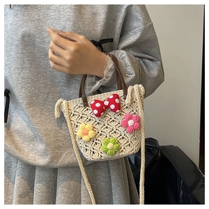 Detail of hand-knitted bucket bag featuring crochet flowers and a polka dot bow
